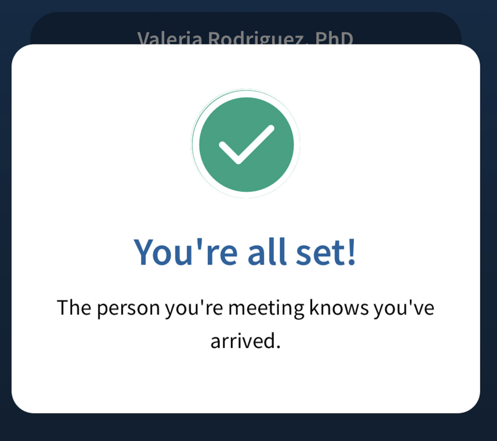 A screenshot of a display on a cell phone which shows a white checkmark on a green background, underneath which is the message, "You're all set! the person you're meeting knows you've arrived."